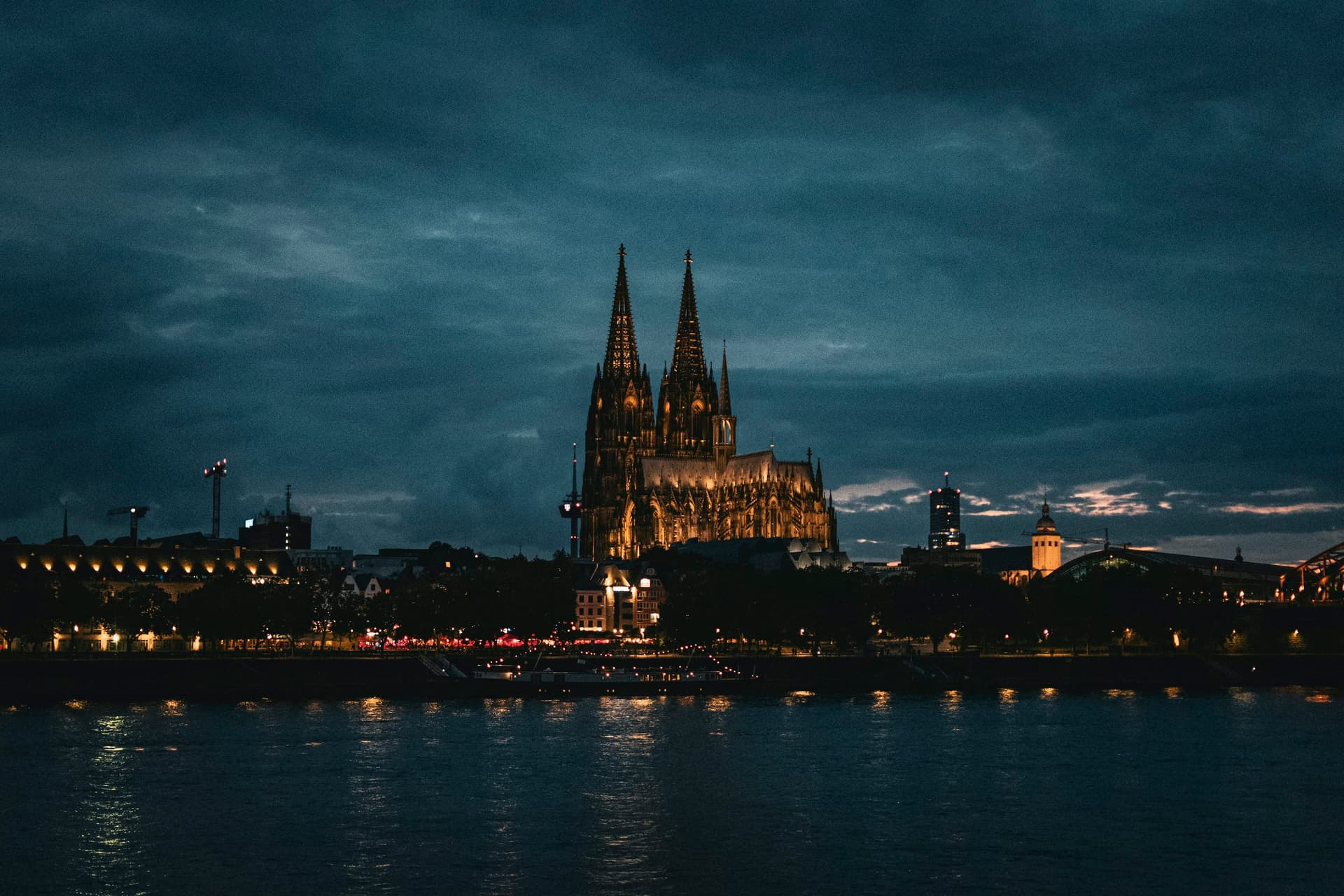 Beleuchteter Kölner Dom bei Nacht, über dem Rhein